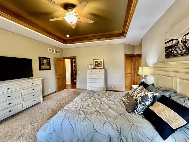 carpeted bedroom with visible vents, baseboards, a tray ceiling, and ceiling fan