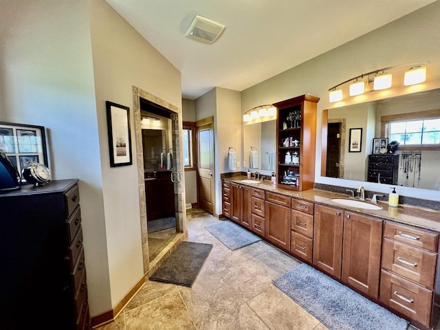 full bathroom featuring double vanity, a stall shower, and a sink