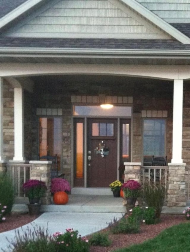 property entrance featuring a porch and stone siding