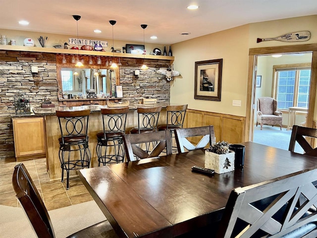 dining room with light tile patterned flooring, a wainscoted wall, and recessed lighting