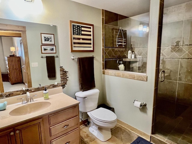 bathroom with a shower stall, vanity, baseboards, toilet, and tile patterned flooring