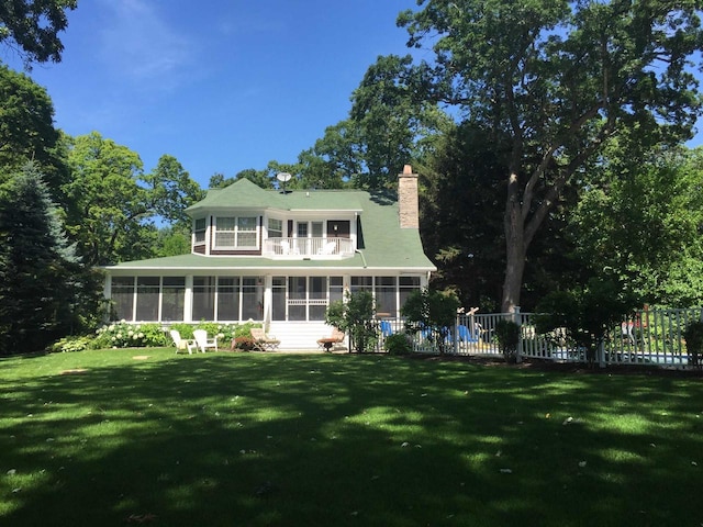 549 Illinois Ave, Green Lake, WI 54941 - rear view of house featuring a sunroom, a lawn, fence, a balcony, and a chimney