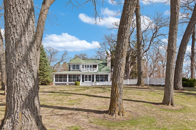 549 Illinois Ave, Green Lake, WI 54941 - view of front facade featuring a balcony, a chimney, a front lawn, a sunroom, and fence