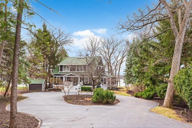 549 Illinois Ave, Green Lake, WI 54941 - view of front of house featuring a porch, curved driveway, a storage unit, and an outdoor structure