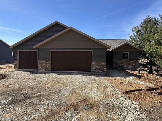 N1647 21st Ave, Wautoma, WI 54982 - view of front of home with an attached garage, stone siding, and dirt driveway