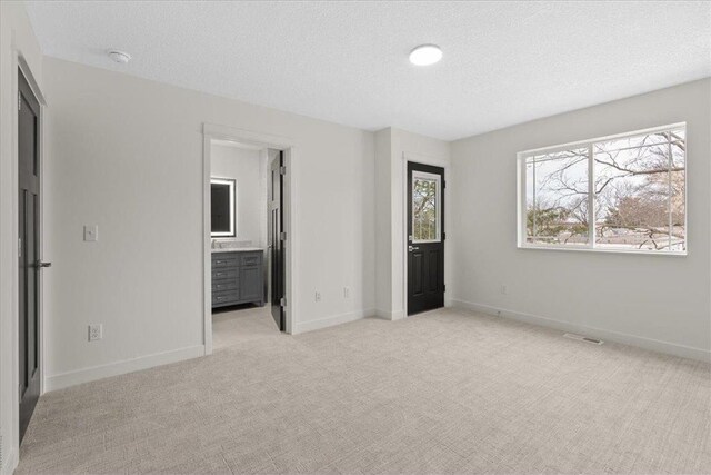 425 W 8th St Unit 20, New Richmond, WI 54017 - unfurnished bedroom featuring baseboards, a textured ceiling, and light carpet