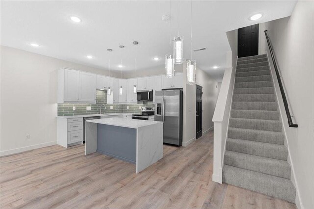 425 W 8th St Unit 20, New Richmond, WI 54017 - kitchen with light countertops, light wood finished floors, stainless steel appliances, tasteful backsplash, and a center island