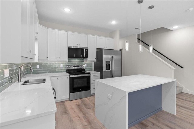 425 W 8th St Unit 20, New Richmond, WI 54017 - kitchen featuring a sink, white cabinetry, tasteful backsplash, light wood-style flooring, and stainless steel appliances