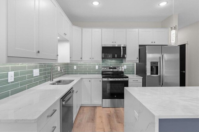 425 W 8th St Unit 20, New Richmond, WI 54017 - kitchen featuring tasteful backsplash, a sink, light wood-style floors, light stone counters, and appliances with stainless steel finishes