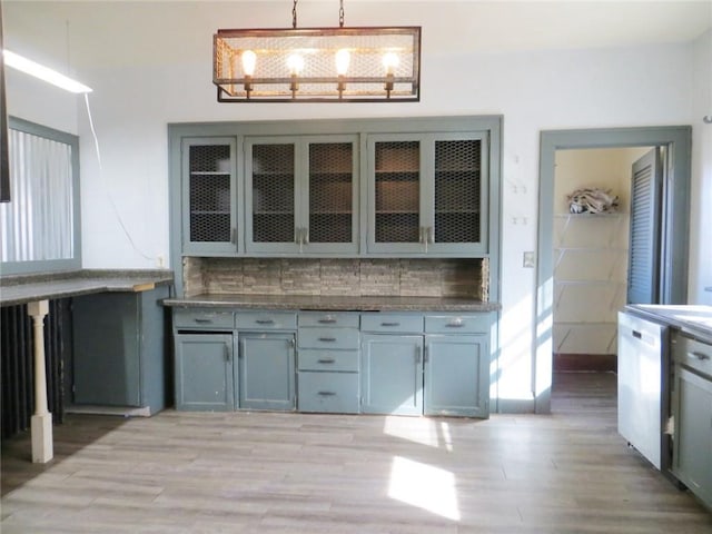 204 W Main St, Thorp, WI 54771 - kitchen featuring decorative backsplash, glass insert cabinets, light wood-style floors, hanging light fixtures, and white dishwasher