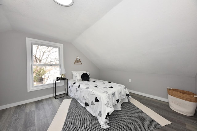 bedroom featuring baseboards, vaulted ceiling, and wood finished floors