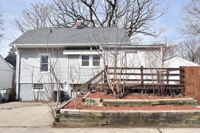 view of front facade with driveway, central AC unit, a deck, a shingled roof, and a chimney