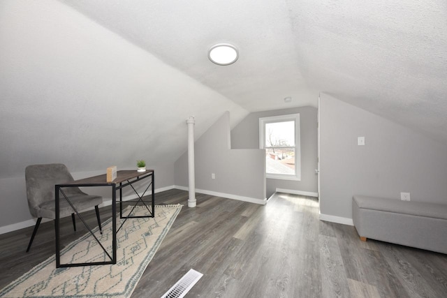 office area with a textured ceiling, visible vents, baseboards, wood finished floors, and lofted ceiling