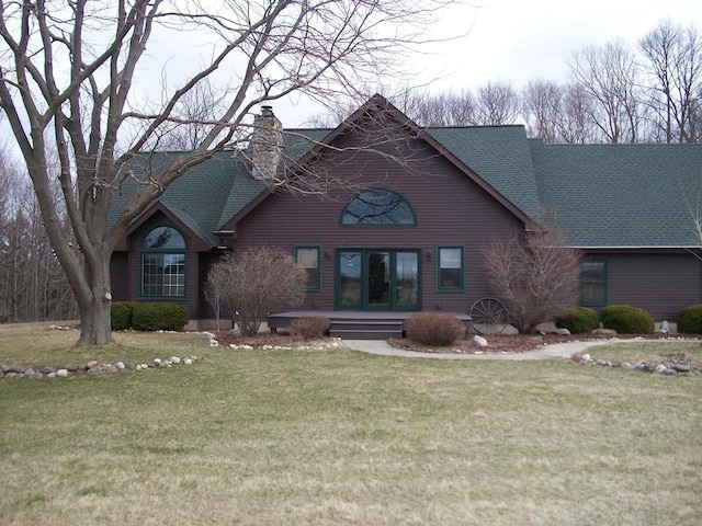 view of front facade featuring a chimney, a shingled roof, and a front lawn