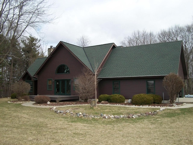view of front of home featuring a wooden deck, a chimney, a shingled roof, and a front lawn