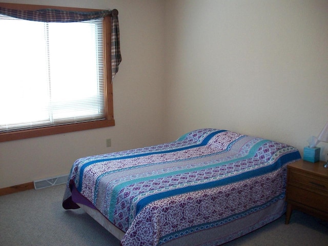 carpeted bedroom featuring baseboards and visible vents