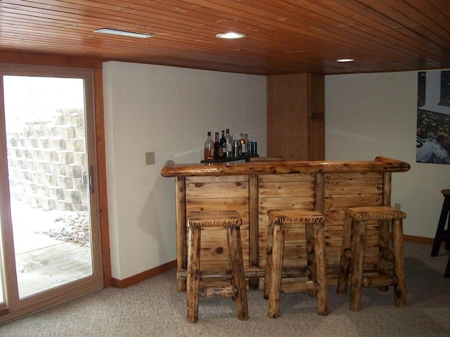 bar with a bar, carpet flooring, wood ceiling, and baseboards