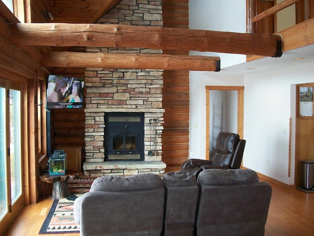 living area featuring beam ceiling, a fireplace, light wood-style flooring, baseboards, and a towering ceiling