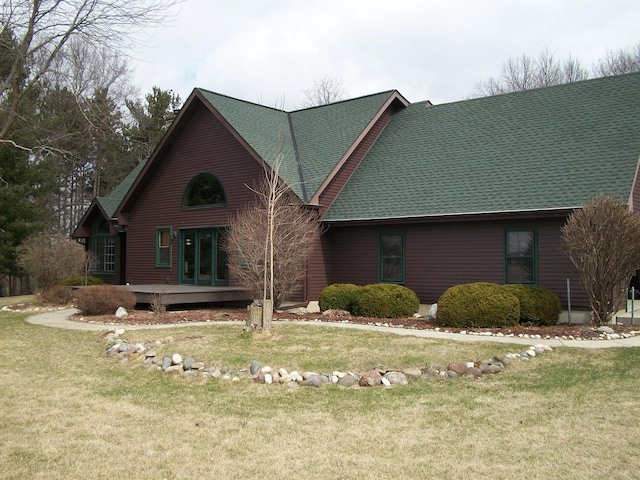 view of front of home featuring a front lawn, a wooden deck, and roof with shingles