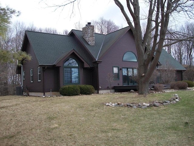 view of front of house featuring central AC unit, a front yard, a shingled roof, and a chimney
