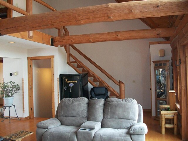 living room with stairs, wood finished floors, and beam ceiling