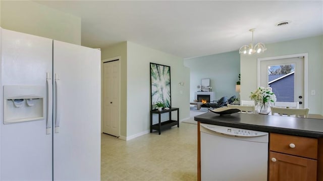 27183 250th St, Holcombe, WI 54745 - kitchen featuring white appliances, dark countertops, a warm lit fireplace, a notable chandelier, and light floors
