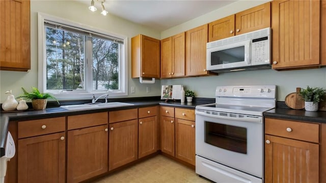 27183 250th St, Holcombe, WI 54745 - kitchen with white appliances, a sink, dark countertops, brown cabinetry, and light floors
