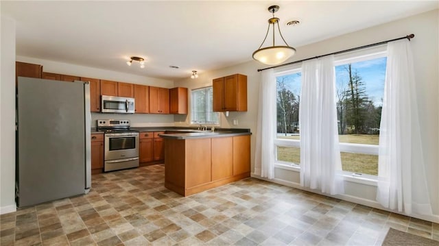 27183 250th St, Holcombe, WI 54745 - kitchen featuring visible vents, a peninsula, stainless steel appliances, decorative light fixtures, and brown cabinetry