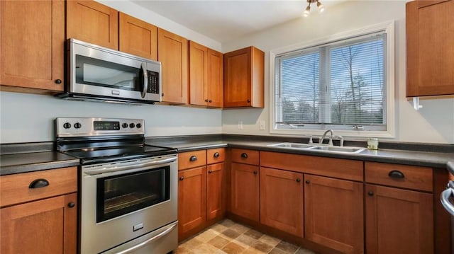 27183 250th St, Holcombe, WI 54745 - kitchen with a sink, dark countertops, appliances with stainless steel finishes, and brown cabinetry
