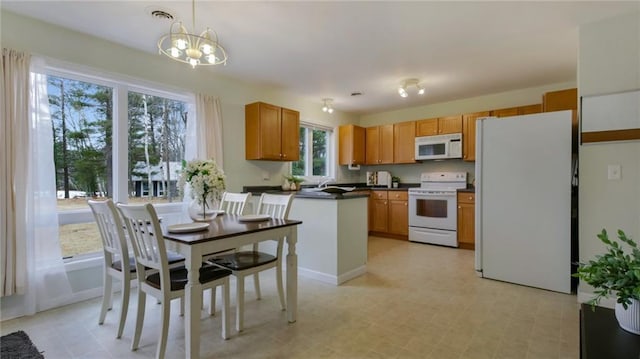 27183 250th St, Holcombe, WI 54745 - kitchen featuring decorative light fixtures, white appliances, a chandelier, dark countertops, and a peninsula