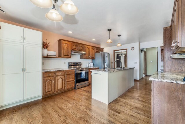 2015 Hickory Ln, Oshkosh, WI 54901 - kitchen with stainless steel appliances, light wood finished floors, a sink, and decorative backsplash