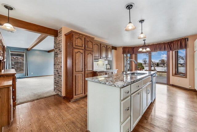 2015 Hickory Ln, Oshkosh, WI 54901 - kitchen with an island with sink, light stone countertops, light wood-style floors, beam ceiling, and a sink