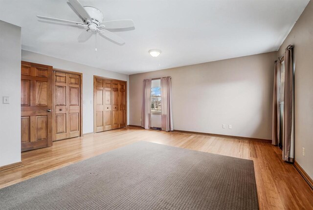 2015 Hickory Ln, Oshkosh, WI 54901 - unfurnished bedroom with light wood-style flooring, baseboards, multiple closets, and ceiling fan