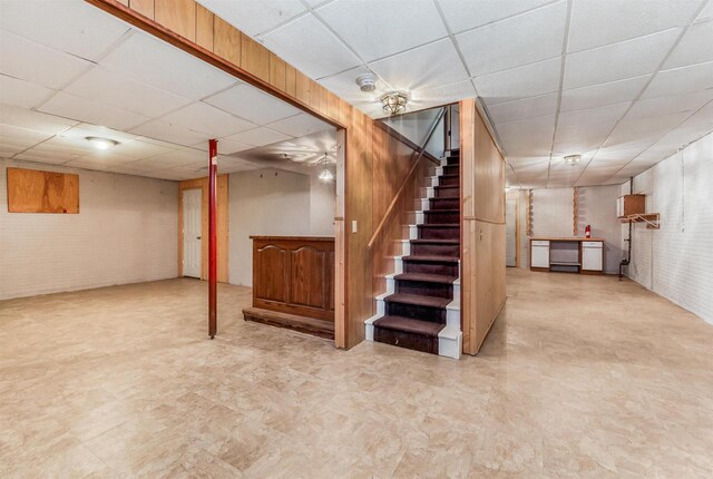 2015 Hickory Ln, Oshkosh, WI 54901 - finished below grade area featuring a paneled ceiling, brick wall, tile patterned floors, and stairs
