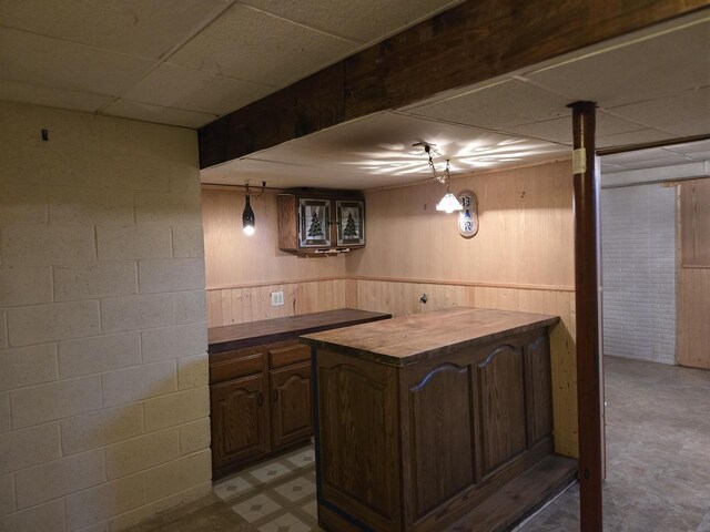 2015 Hickory Ln, Oshkosh, WI 54901 - bar featuring a drop ceiling, a wainscoted wall, concrete block wall, tile patterned floors, and wooden walls