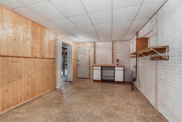 2015 Hickory Ln, Oshkosh, WI 54901 - below grade area with brick wall, tile patterned floors, wooden walls, and a paneled ceiling