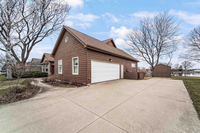 2015 Hickory Ln, Oshkosh, WI 54901 - view of home's exterior with an outbuilding, a water view, a storage unit, an attached garage, and driveway