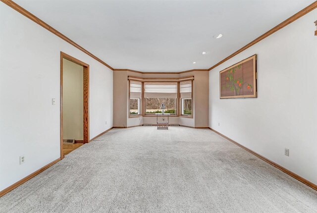 2015 Hickory Ln, Oshkosh, WI 54901 - carpeted empty room with crown molding, baseboards, and visible vents