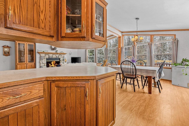 843 Sundstein Rd, Eagle River, WI 54521 - kitchen with light wood-style flooring, brown cabinets, a chandelier, light countertops, and crown molding