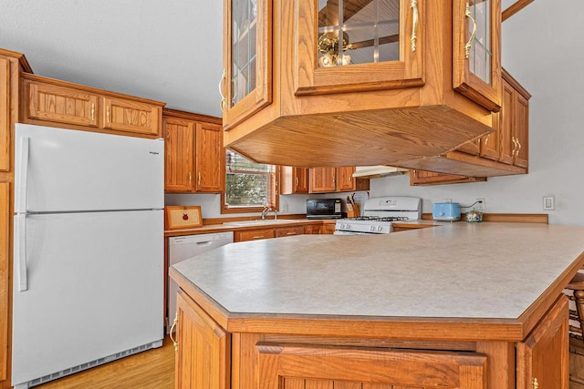 843 Sundstein Rd, Eagle River, WI 54521 - kitchen featuring white appliances, brown cabinets, glass insert cabinets, and under cabinet range hood