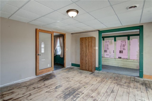 W1797 County Road A, Mindoro, WI 54644 - unfurnished room with visible vents, baseboards, a drop ceiling, and hardwood / wood-style flooring