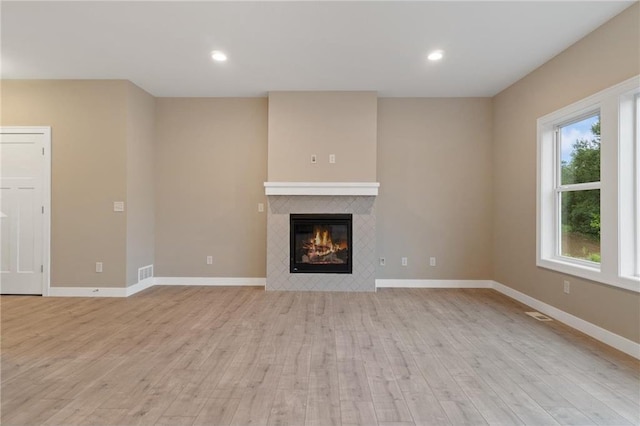 721 Jacko Ct, Hudson, WI 54016 - unfurnished living room with baseboards, visible vents, a tiled fireplace, and light wood-style flooring