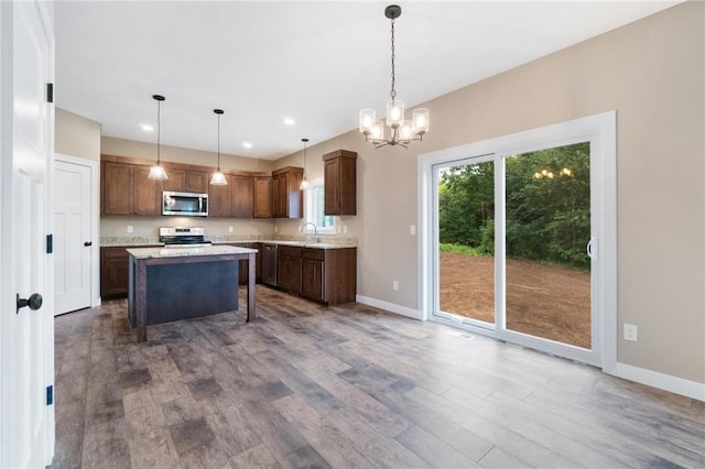 kitchen featuring appliances with stainless steel finishes, wood finished floors, light countertops, a sink, and a notable chandelier