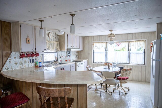 N7363 Wahneeta Ave, New Lisbon, WI 53950 - kitchen with light countertops, a peninsula, white appliances, light floors, and hanging light fixtures