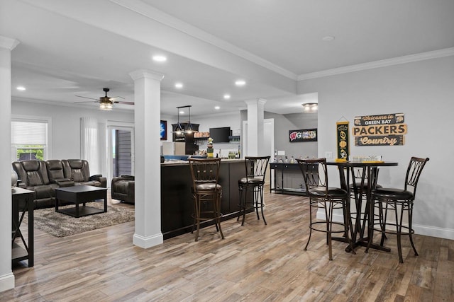 6612 Florance Ruth Ln, Sun Prairie, WI 53590 - dining room with ornate columns, a ceiling fan, crown molding, light wood-type flooring, and a bar