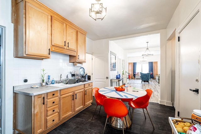 kitchen with light countertops, tasteful backsplash, a sink, pendant lighting, and light brown cabinets