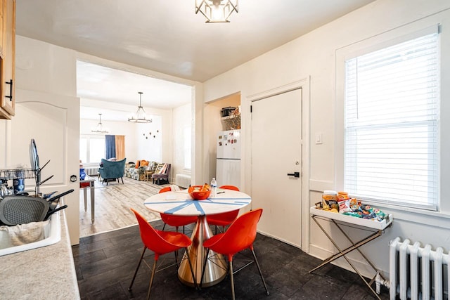 dining room with radiator heating unit, a notable chandelier, and dark wood finished floors