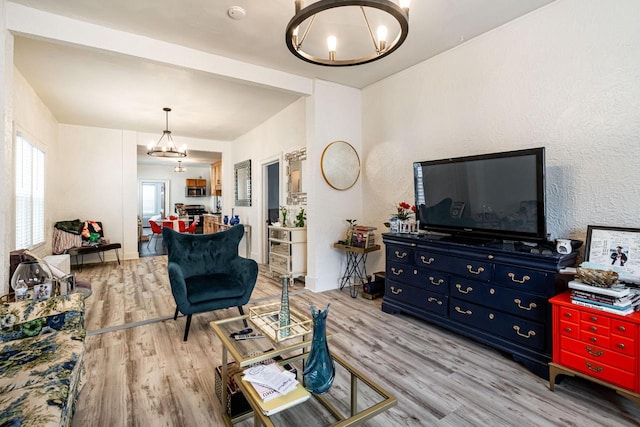living area with a textured wall, wood finished floors, and a notable chandelier