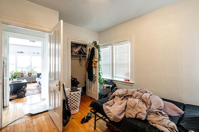 bedroom with a closet, a textured wall, and light wood finished floors