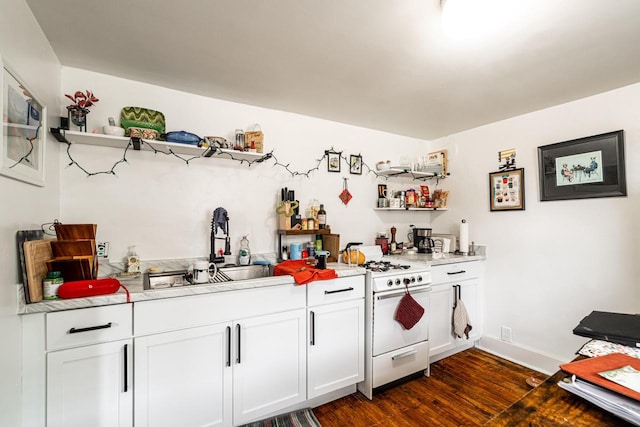 kitchen with light countertops, a sink, open shelves, white gas stove, and dark wood-type flooring